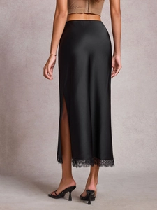 Détail d'une jupe en satin noir avec dentelle délicate et fente latérale élégante