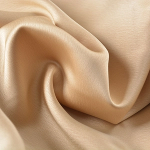 Vue détaillée du tissu satiné champagne montrant sa texture soyeuse et son fini brillant