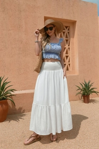 Detail view of high-waist tiered white maxi skirt with elastic smocking and side pockets