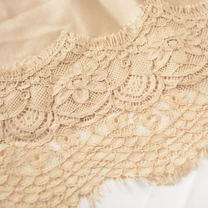 Détail d'une jupe en satin champagne élégante avec bordure en dentelle florale fine