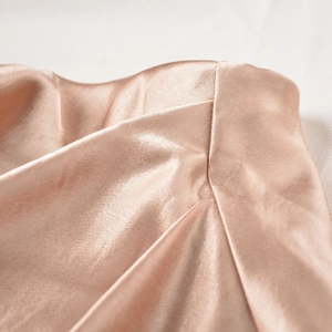 Detailed macro view of champagne satin fabric showing fine texture and elegant pleated folds