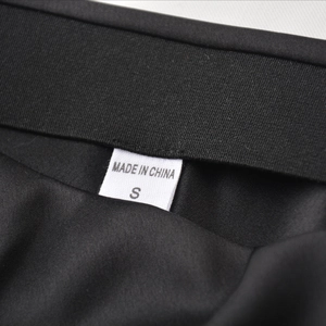 Détail de la taille de la jupe en satin noir montrant l'étiquette S et Made in China
