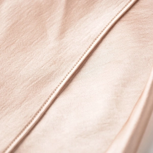 Detail shot of elegant champagne satin skirt featuring premium hem stitching and silky texture