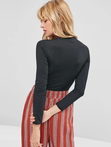 Detail view of the black ribbed knit texture and slim fit high neck long sleeve top