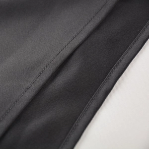 Détail du tissu en satin noir montrant des coutures fines et une texture soyeuse lisse