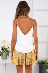 Back view of a model in a white backless camisole and yellow floral ruffle skirt