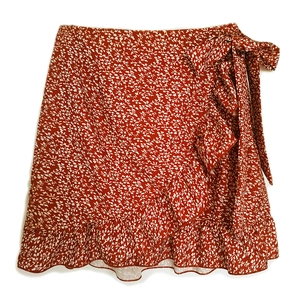 Detail of red floral wrap skirt with tie-waist bow and elegant ruffled hem design