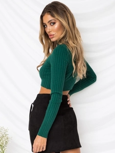 Detail showing dark green ribbed knit long sleeve crop top with black mini skirt texture