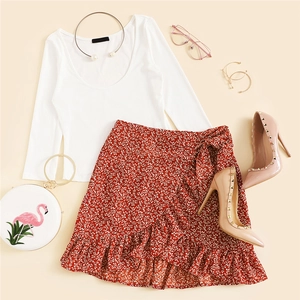 Flat lay of white ribbed long sleeve top and red floral ruffle skirt with fashion accessories