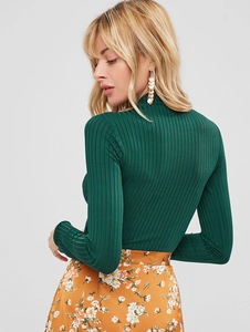 Detail of dark green ribbed knit long sleeve top featuring a slim fit and high neckline