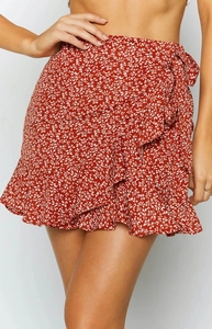 Detail of red floral wrap skirt with ruffle hem and side tie belt in light chiffon fabric