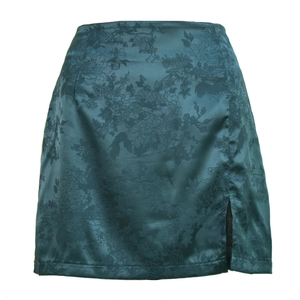 Détail d'une jupe en satin jacquard vert foncé avec motif floral et fente latérale