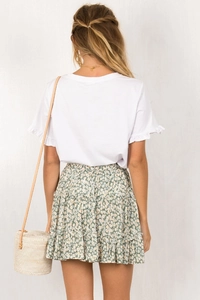 Detail view of white ruffled sleeve top and green floral tiered skirt on a fashion model