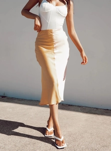 Detailsicht auf einen champagnergoldenen Satin-Midirock mit elegantem Bustier-Top