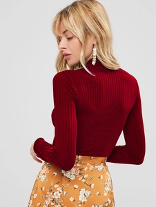 Detailed view of burgundy ribbed long sleeve turtleneck top on model with floral skirt