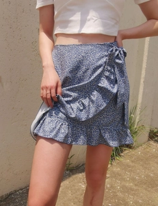 Detail of blue floral wrap skirt with ruffle hem and waist tie in outdoor sunlight
