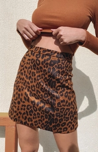 Détail d'une mini-jupe en daim à imprimé léopard et d'un haut court en maille orange