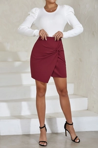 Détail de la mini-jupe portefeuille bordeaux avec nœud à la taille et texture froncée