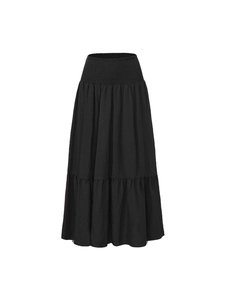 Detail of smocked elastic waistband and tiered cotton fabric on a black A-line maxi skirt