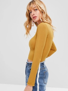 Detail of mustard yellow ribbed long sleeve crop top with a close-up of the knit texture