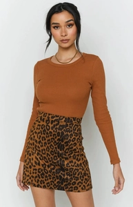 Détail d'une mini-jupe léopard taille haute assortie à un haut en maille caramel
