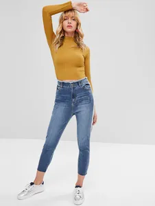 Detail of mustard yellow ribbed knit top with high-waist jeans and raw hem finish