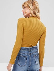 Detail view of the vertical ribbed texture and back fit of this mustard yellow knit top