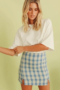 Détail de la mini-jupe à carreaux taille haute avec fentes latérales et t-shirt blanc décontracté