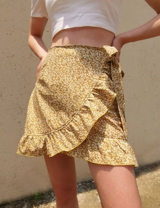 Detailed close-up of mustard yellow floral wrap skirt with ruffle edges and tiered layers