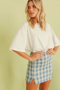 Détail d'une mini-jupe à carreaux taille haute avec fente latérale et t-shirt blanc