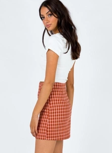 Vue latérale de la mini-jupe à carreaux taille haute avec fente et crop top blanc