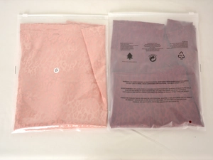 Détail de jupes en satin à motif léopard rose et rouge emballées dans des sacs zippés S