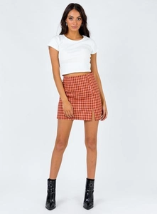 Détail d'une mini-jupe à carreaux rouges à taille haute avec fente et d'un t-shirt blanc court