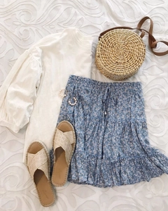 Flat lay of summer floral skirt set with ruffled hem, straw bag and beach sandals
