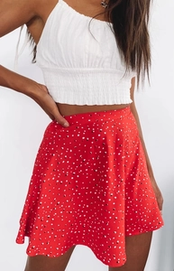 Detail of high waisted red polka dot A-line skirt paired with a white cropped camisole