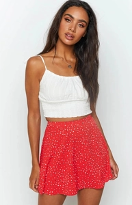 Detail of high-waisted red polka dot floral skirt with soft pleated white camisole top