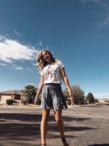 Outdoor shot of a woman in high waist floral mini skirt with drawstring and flower print tee