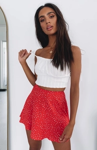 Detail of white smocked camisole top with tie straps and red polka dot chiffon skirt