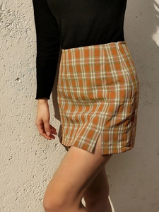 Détail d'une jupe à carreaux taille haute montrant la fente et la texture orange