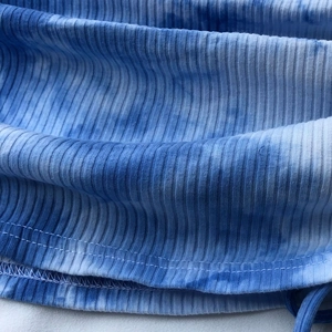 Close-up of blue and white tie-dye ribbed knit fabric with precise bottom stitching