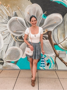 Close-up of high-waist floral tiered mini skirt and white checkered pattern crossbody bag