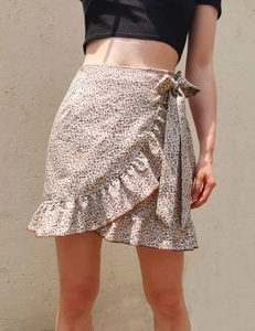 Detail of floral wrap skirt with side tie knot and ruffled hem on light fabric