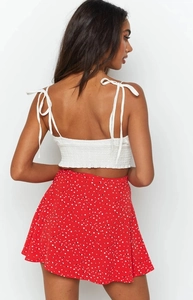 Detail of white pleated tube top with shoulder bows and red polka dot floral skirt