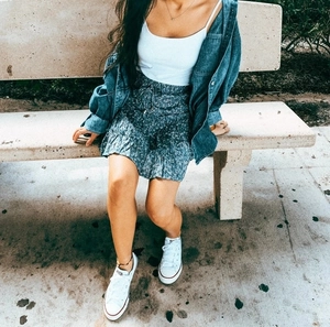 Outdoor shot of a high-waisted blue floral ruffle skirt with a denim jacket and tank top
