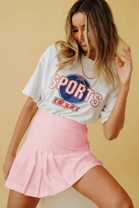Gros plan sur une jupe plissée rose taille haute avec un t-shirt gris à graphique