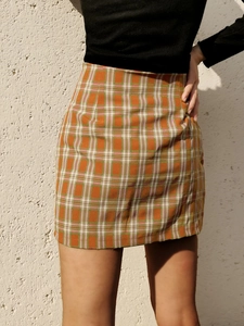 Détail de la texture à carreaux orange et de la fente latérale de la jupe courte