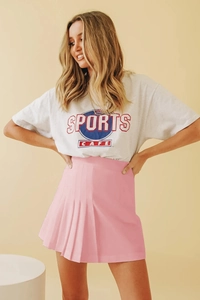 Détail d'une mini-jupe plissée rose taille haute avec un t-shirt vintage imprimé sport
