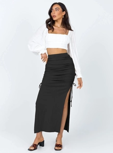 Detail of high waisted black knit skirt featuring side drawstring ruching and a slit