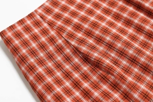 Gros plan sur le tissu à carreaux rouge et orange avec coutures et texture tissée