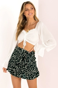Detail of white crop top with drawstring and high waisted ruffle floral mini skirt